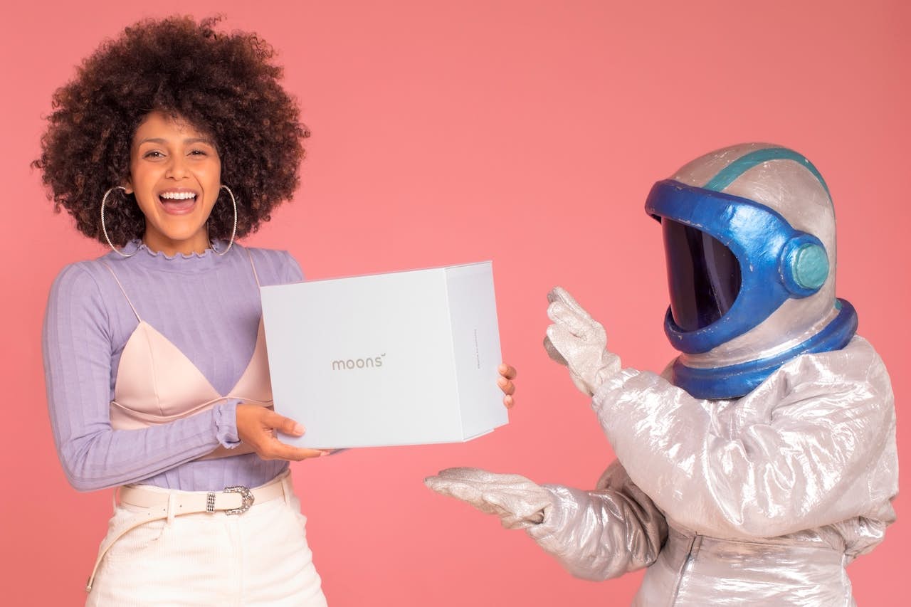 women holding a box next to an a person in astronaut attire