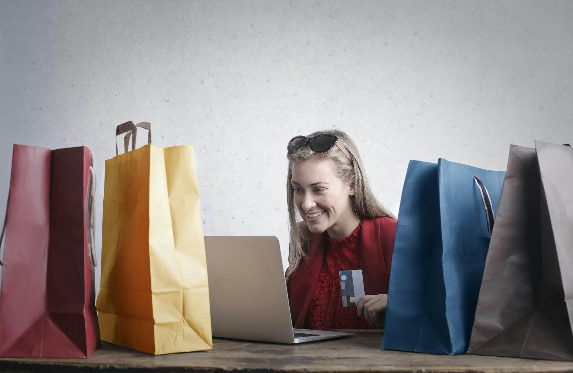 Women smiling at her laptop with shopping bags on her desk