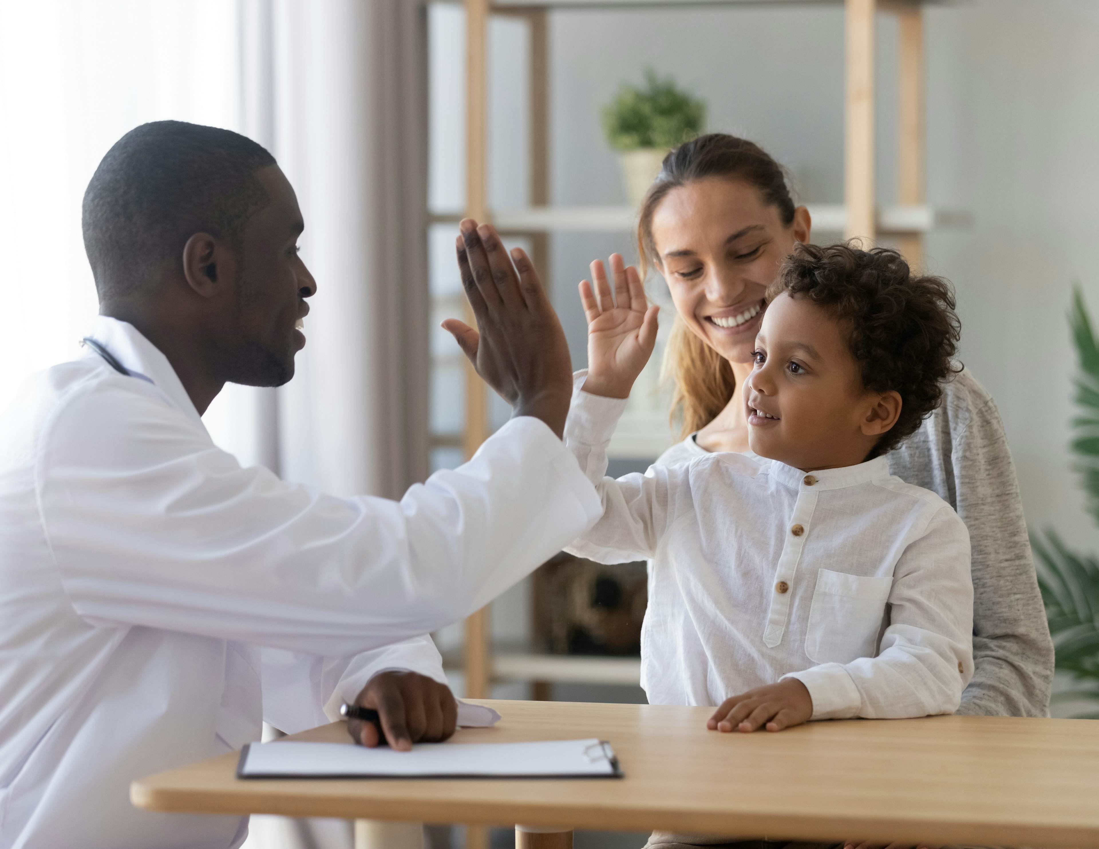 doctor giving child sitting with his mother a high five