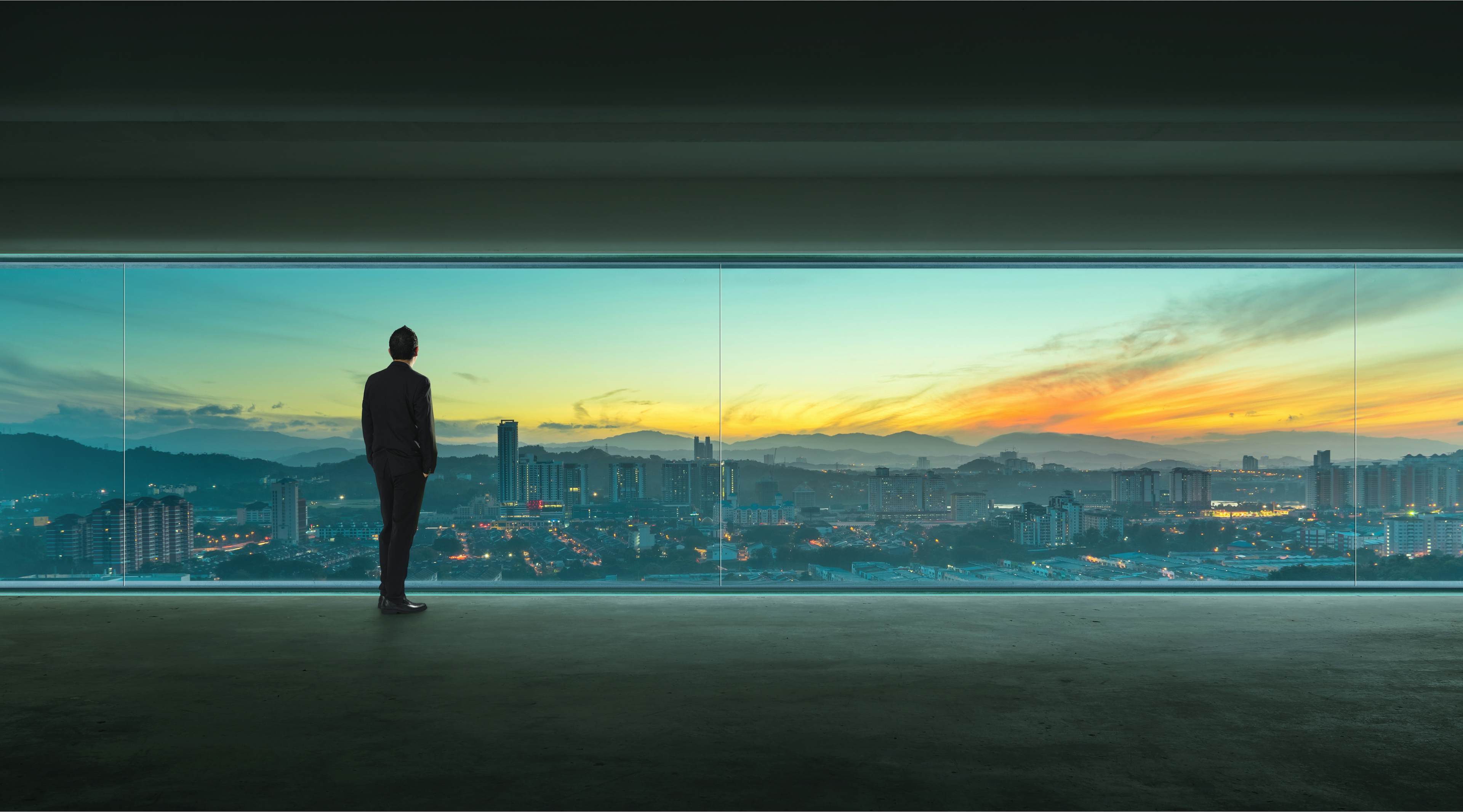 Man looking out window overlooking the city