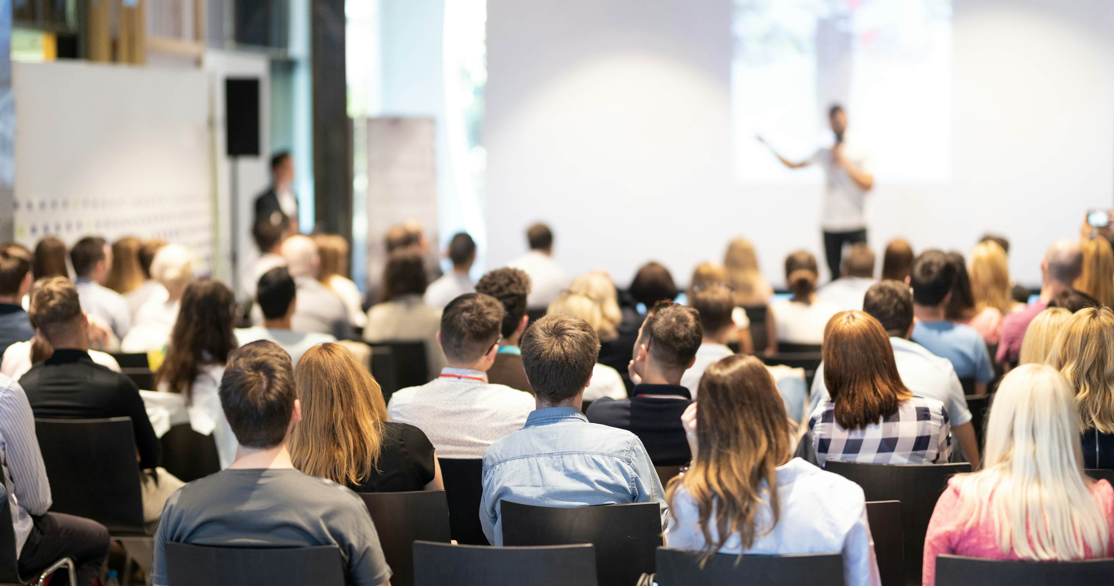 people sitting in a auditorium watching speaker