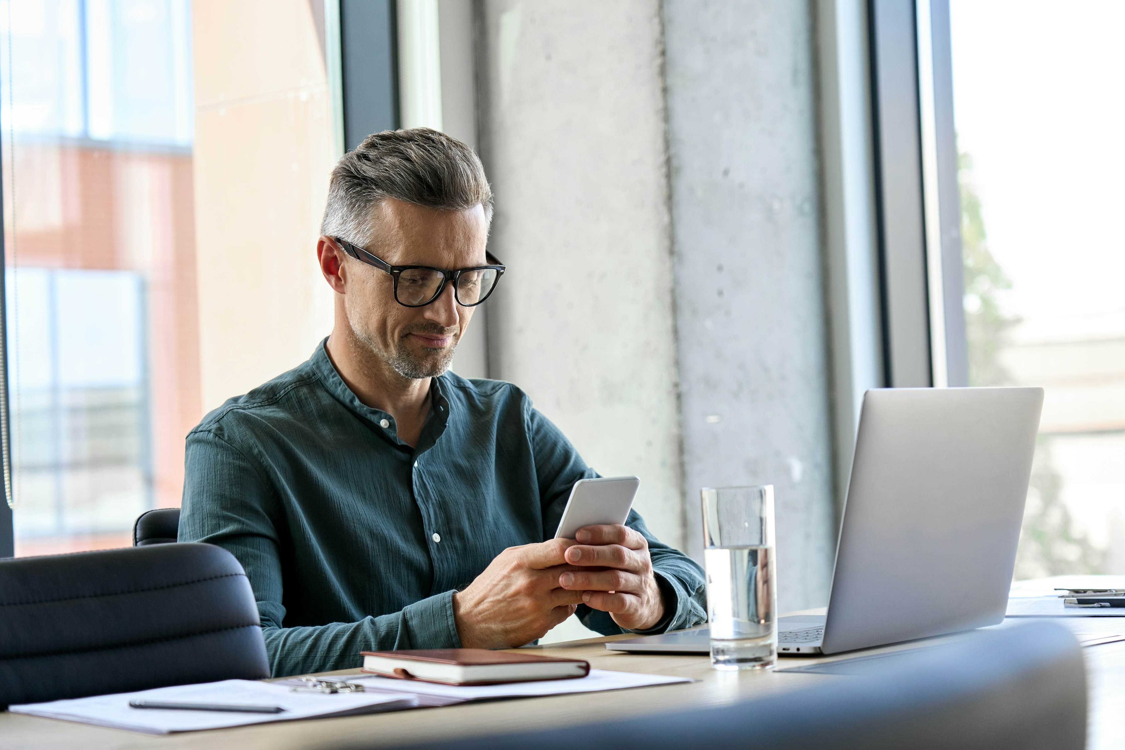 man using cellphone working at office desk