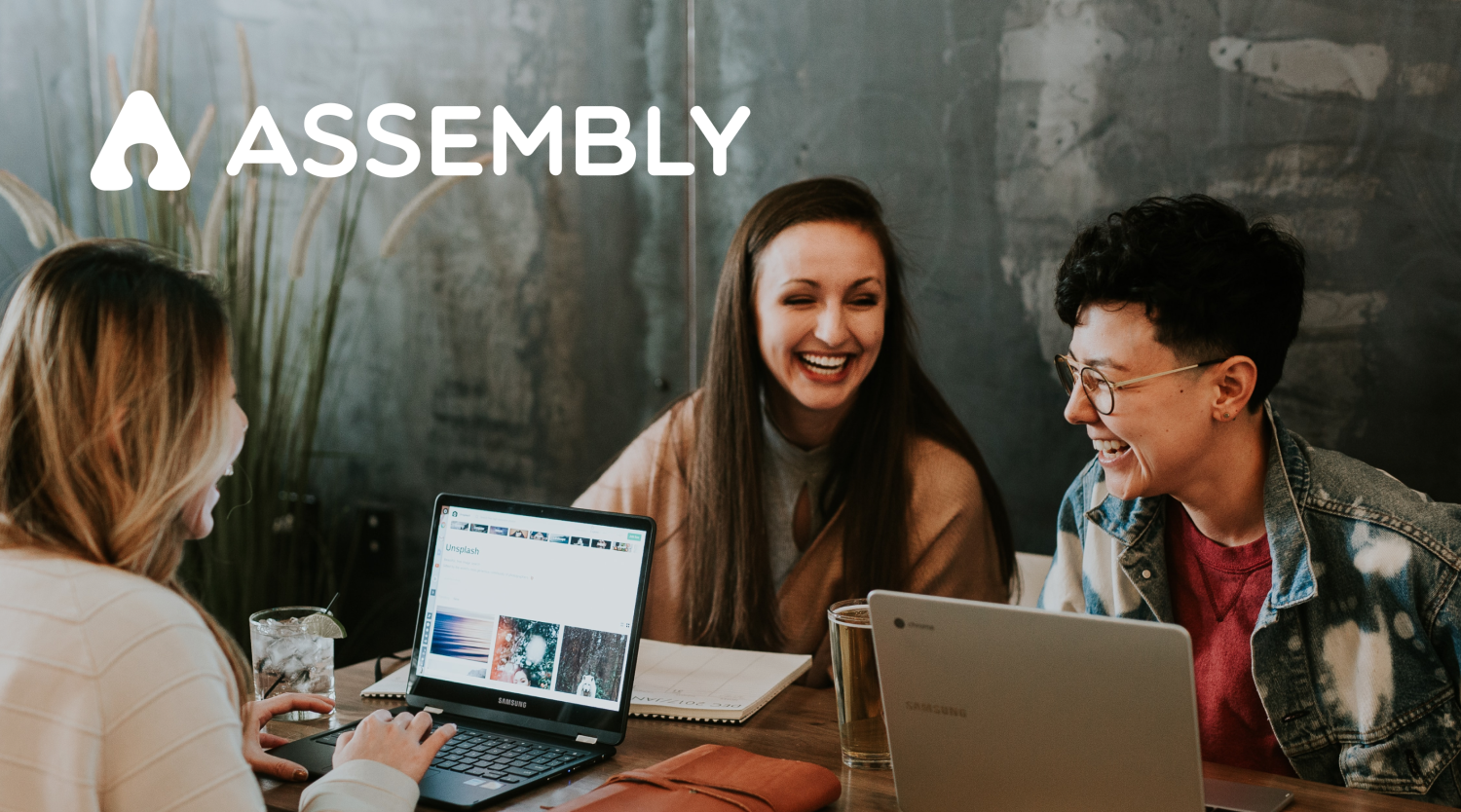 People smiling in front of computers overlay of Assembly logo