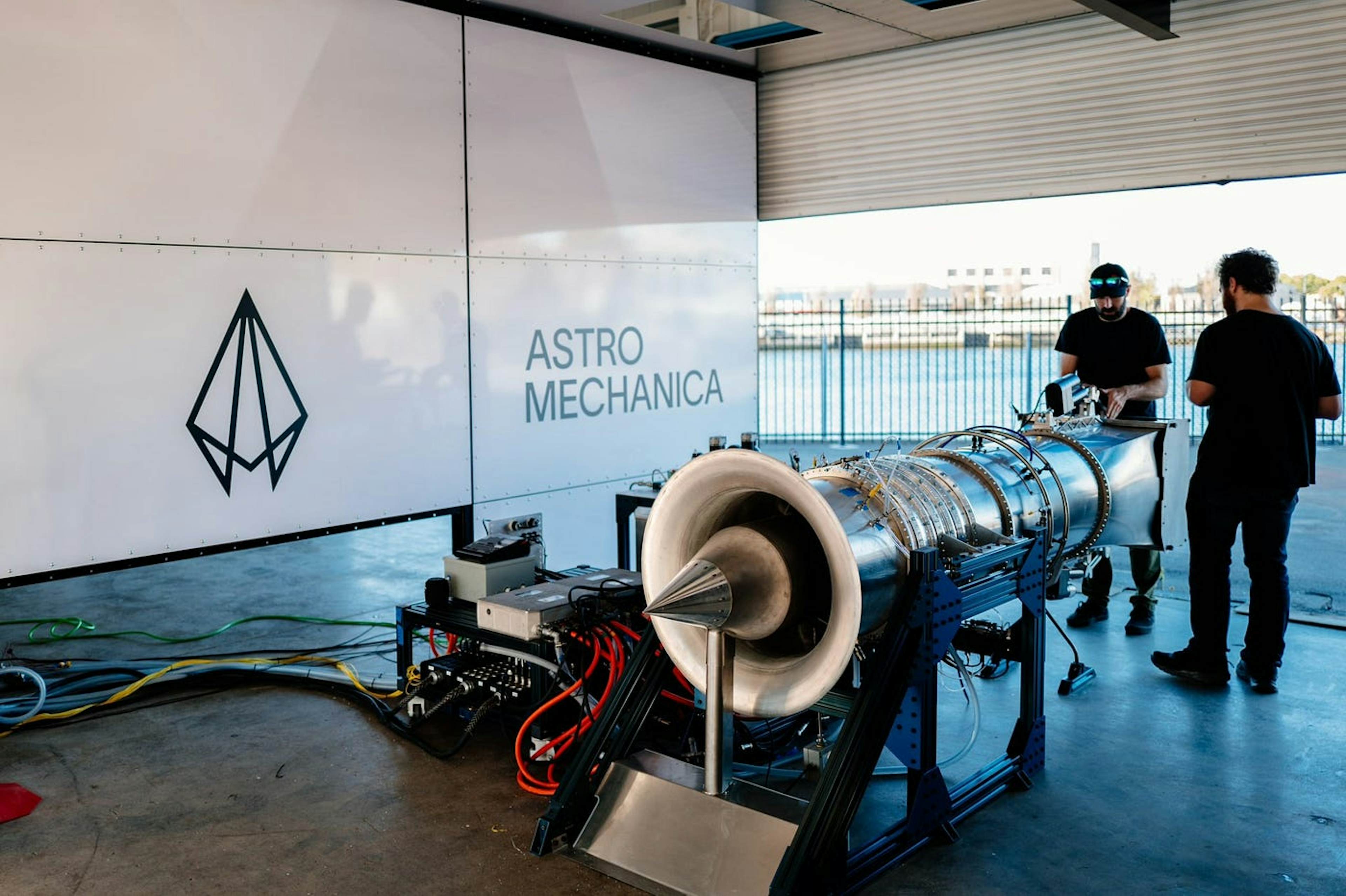 Engineers work on a jet propulsion system at Astro Mechanica’s testing facility near water.