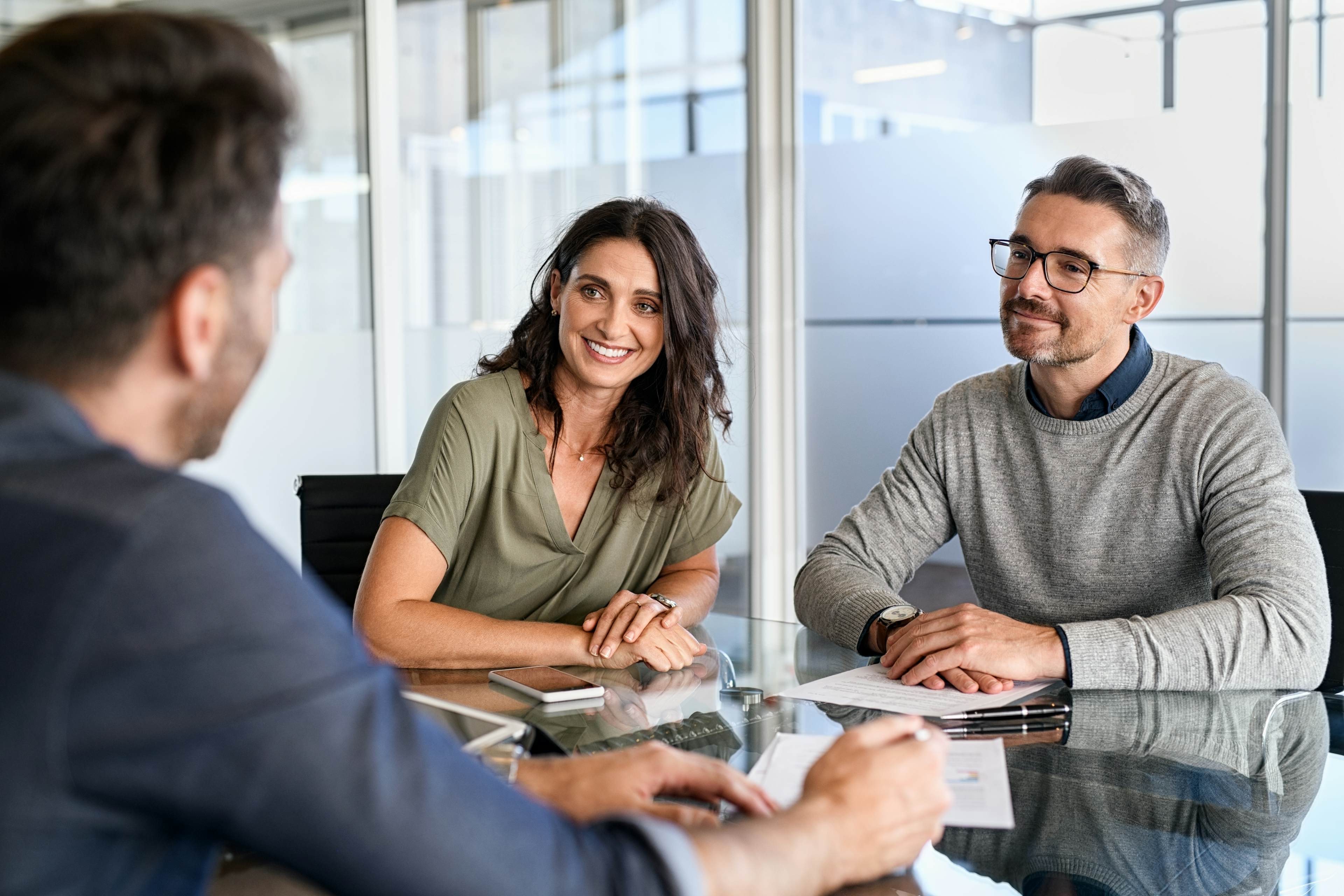 Smiling couple speaking with advisor in office setting
