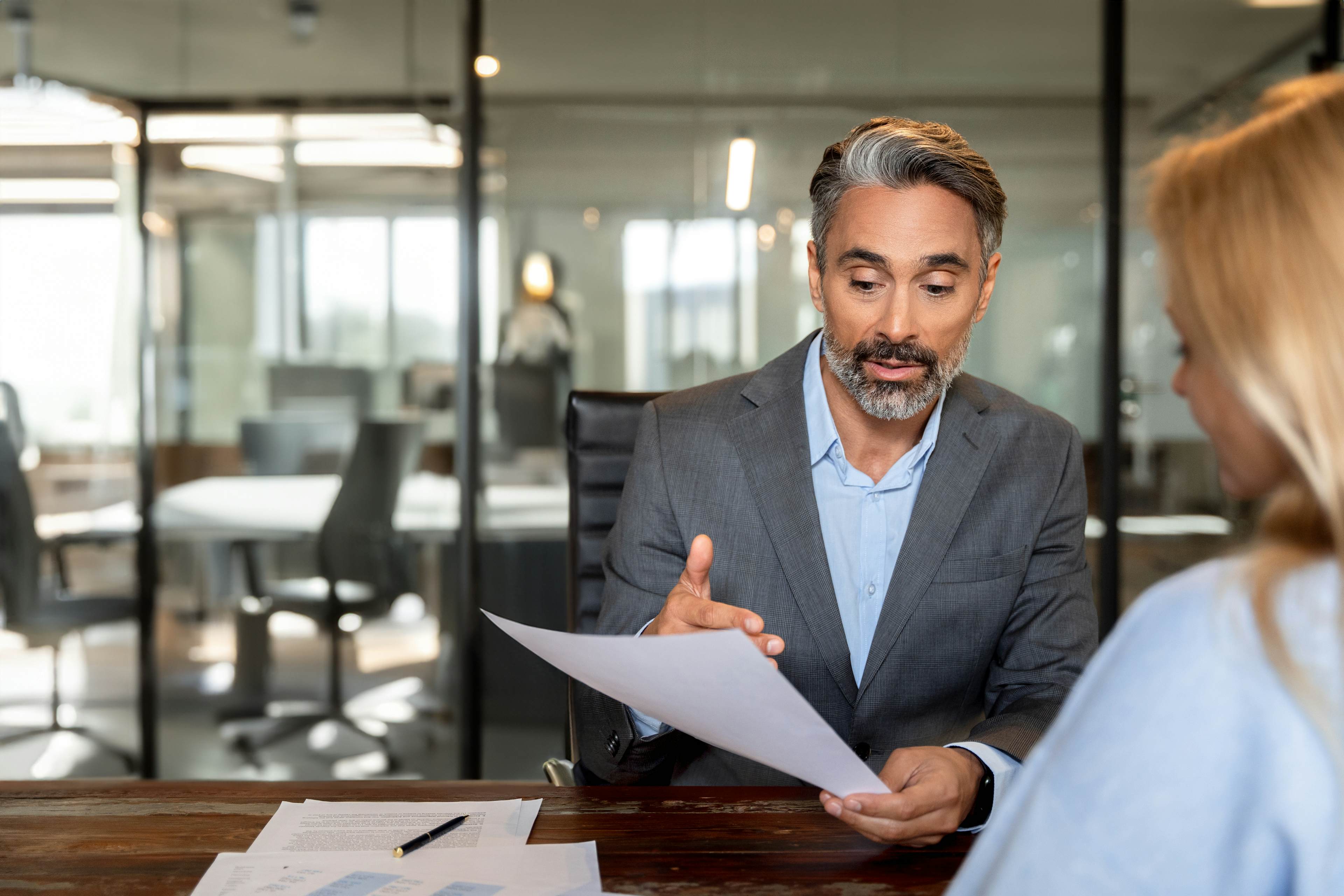 Businessman in a gray suit discussing a document with a colleague