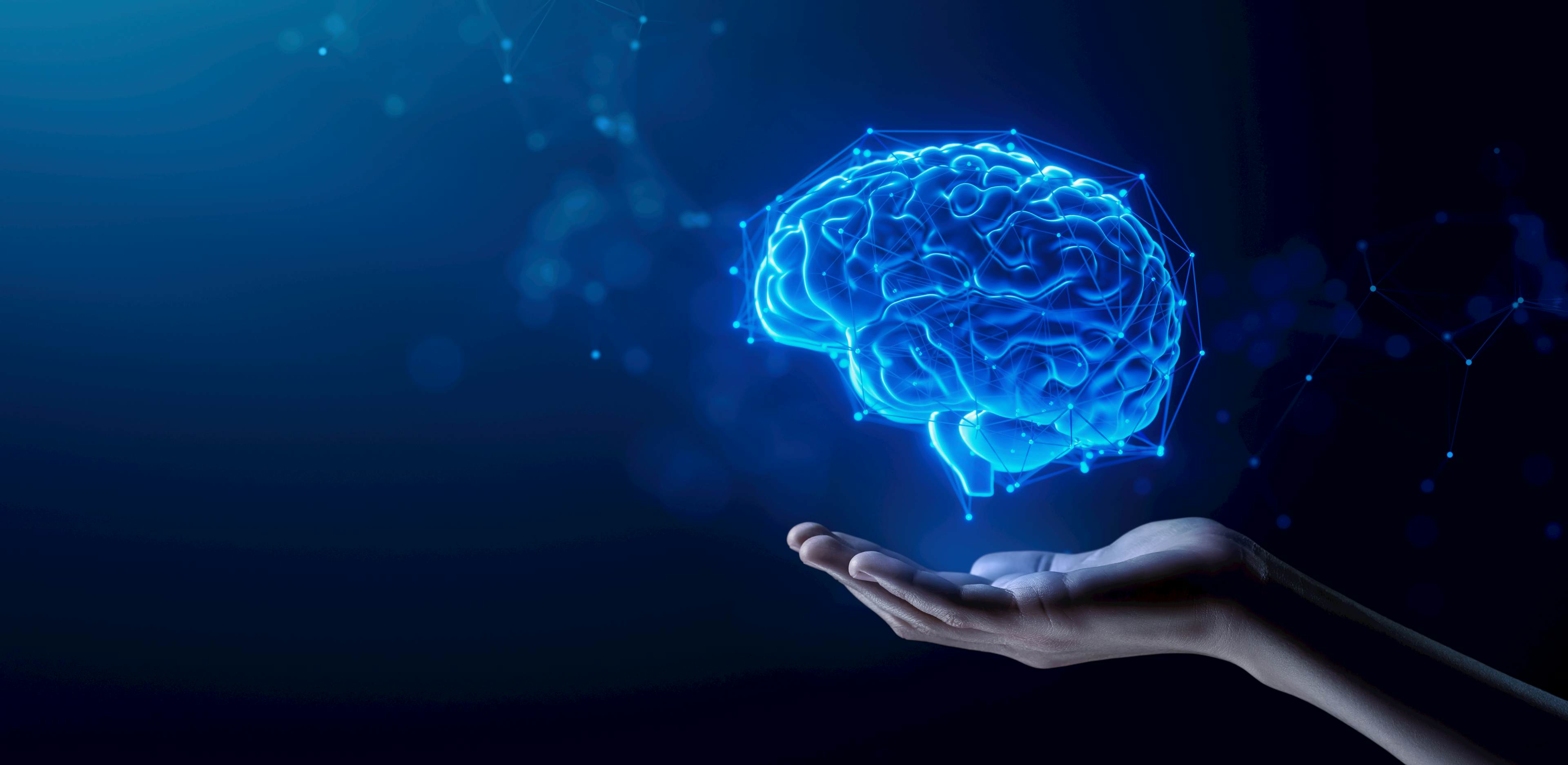 Hand holding an illuminated brain made with blue wires
